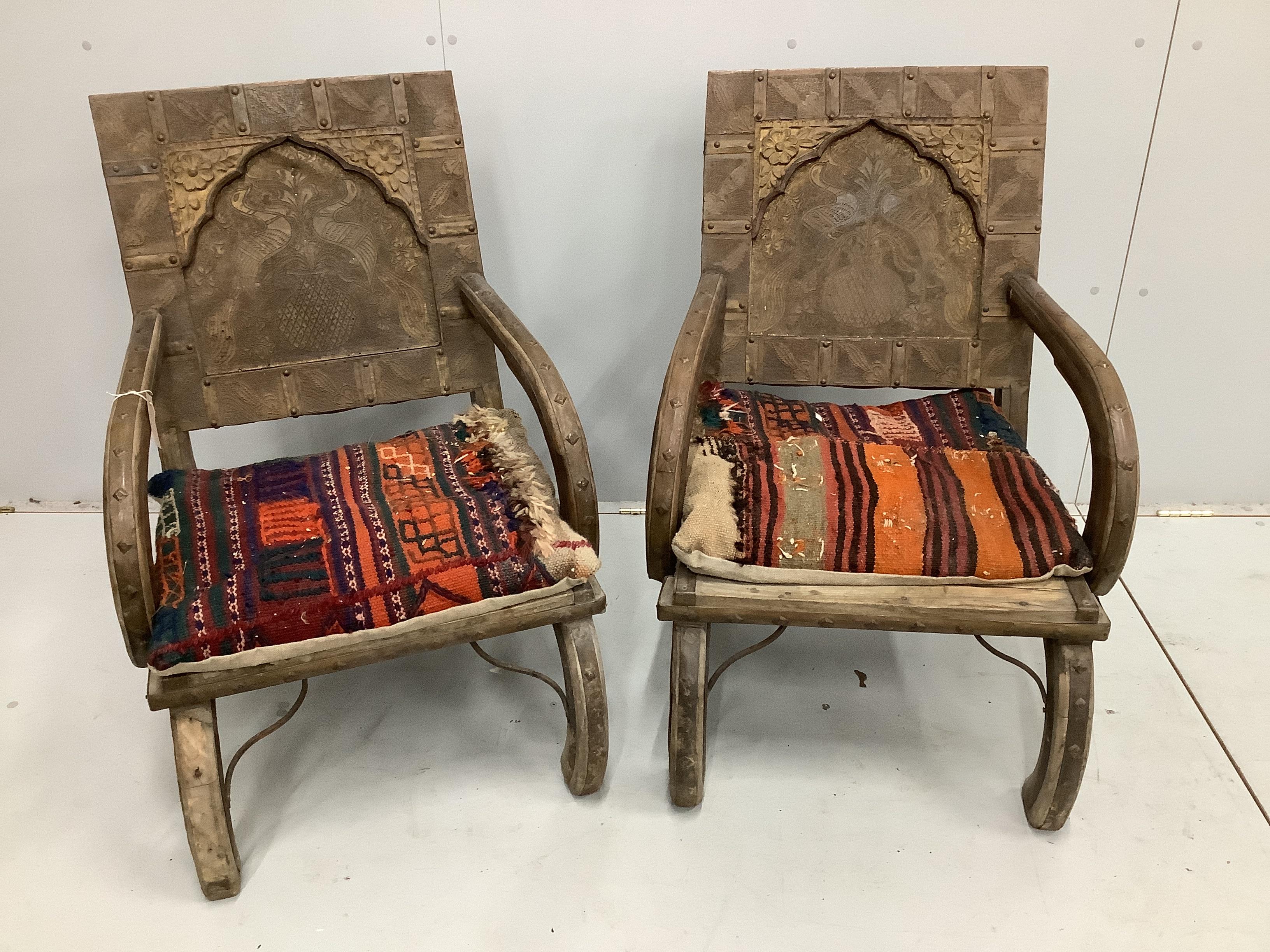 A pair of Indian metal clad low chairs with Kilim covered cushions, width 57cm, depth 48cm, height 89cm